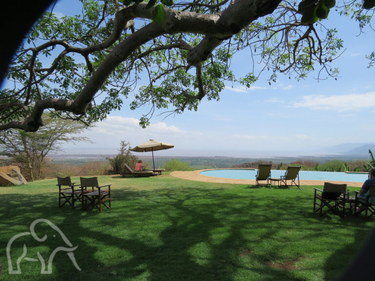 Vanaf een zwembad op een camping in Tanzania kijk je vanaf grote hoogte op Lake Manyara