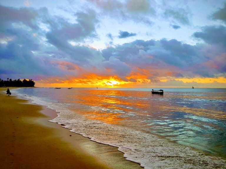 oranje gekleurde zee en wolken afgewisseld met blauwe wolken bij Pangani tijdens een zonsondergang