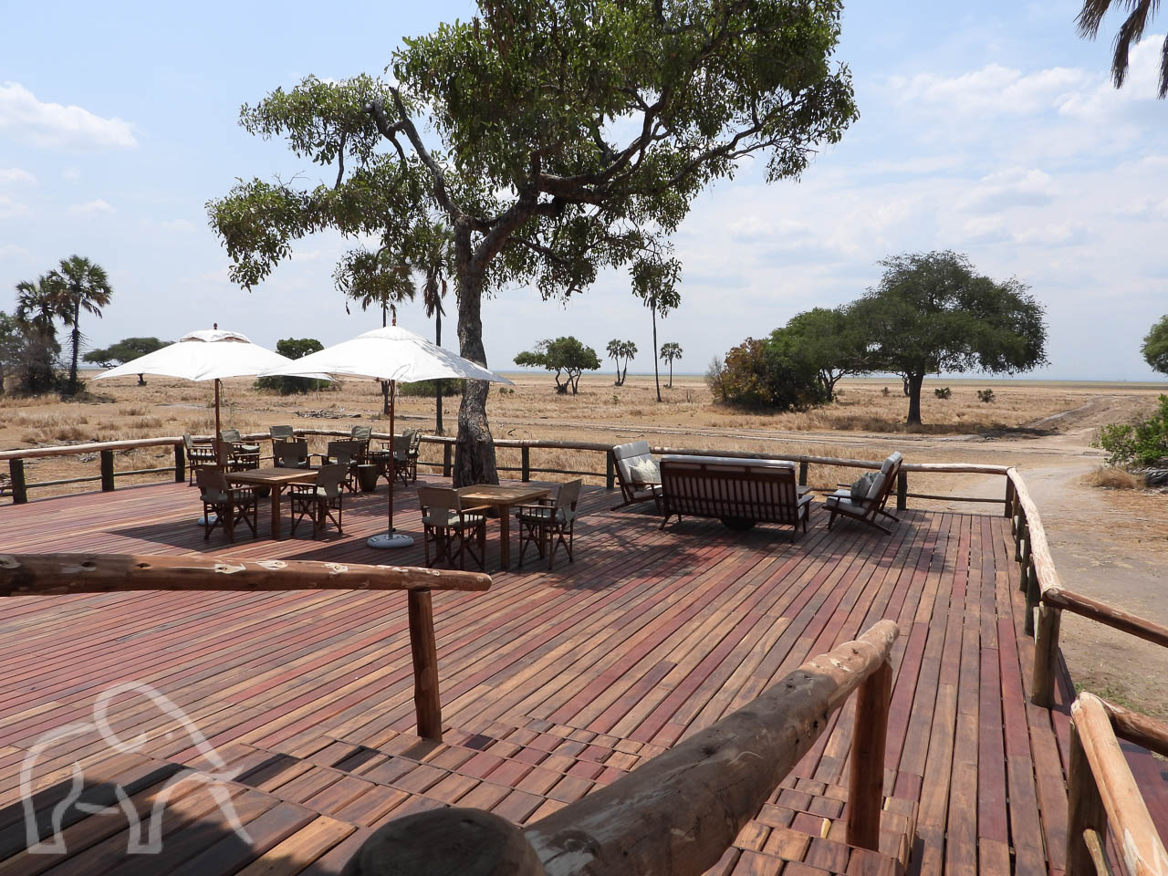 van het terras met tafels en parasollen een uitzicht over de goud gele vlaktes van Katavi
