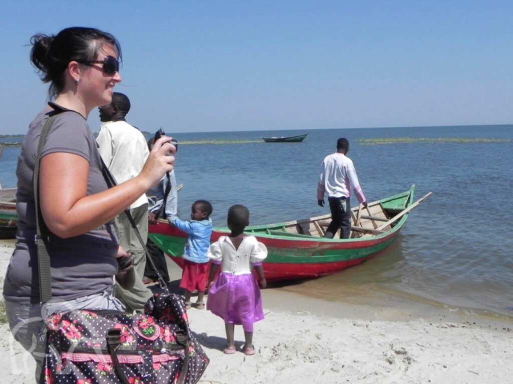 vrouw met camera en twee kleine kinderen die bij een boot kijken met een man erin op lake victoria