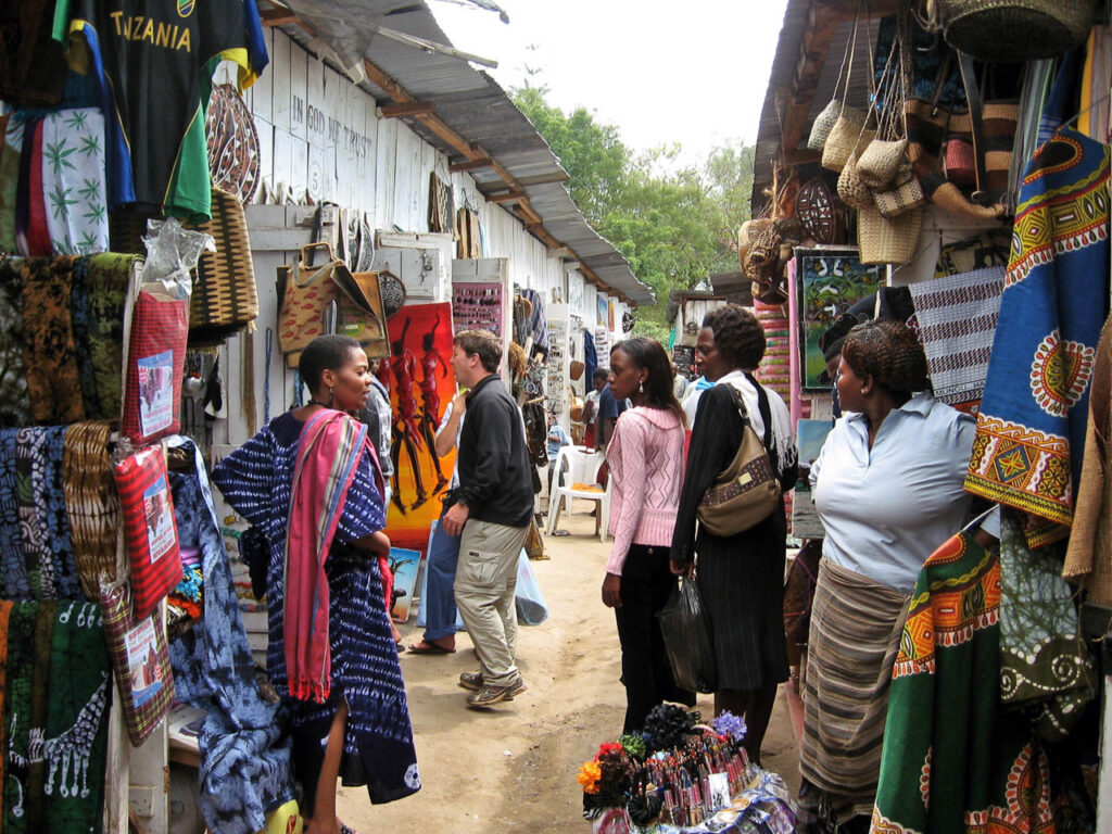 nauw straatje in Arusha met souvenirs winkeltjes en vier vrouwen die met elkaar praten
