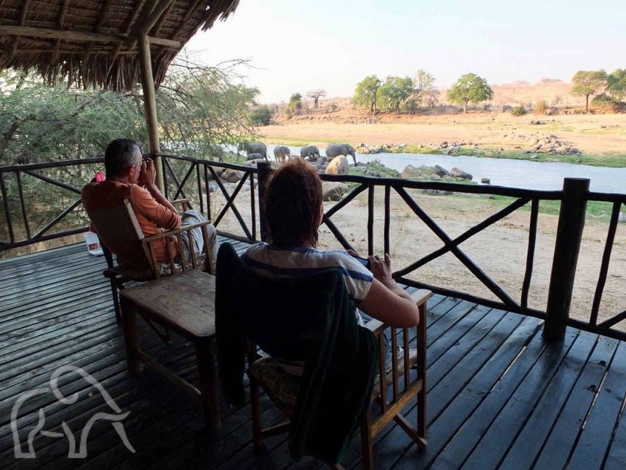 Over ons. Safari Ruaha Tanzania. Oprichters van Droomreis Tanzania zitten op hun veranda en kijken uit over de rivier waar olifanten komen drinken