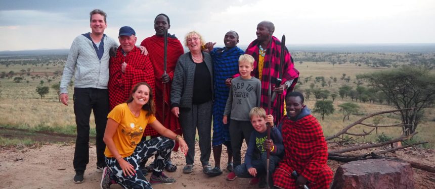 famile met opa oma zoon en schoondochter en kleinkinderen met dire masai mannen tijdens een bezoek aan de masai in tanzania
