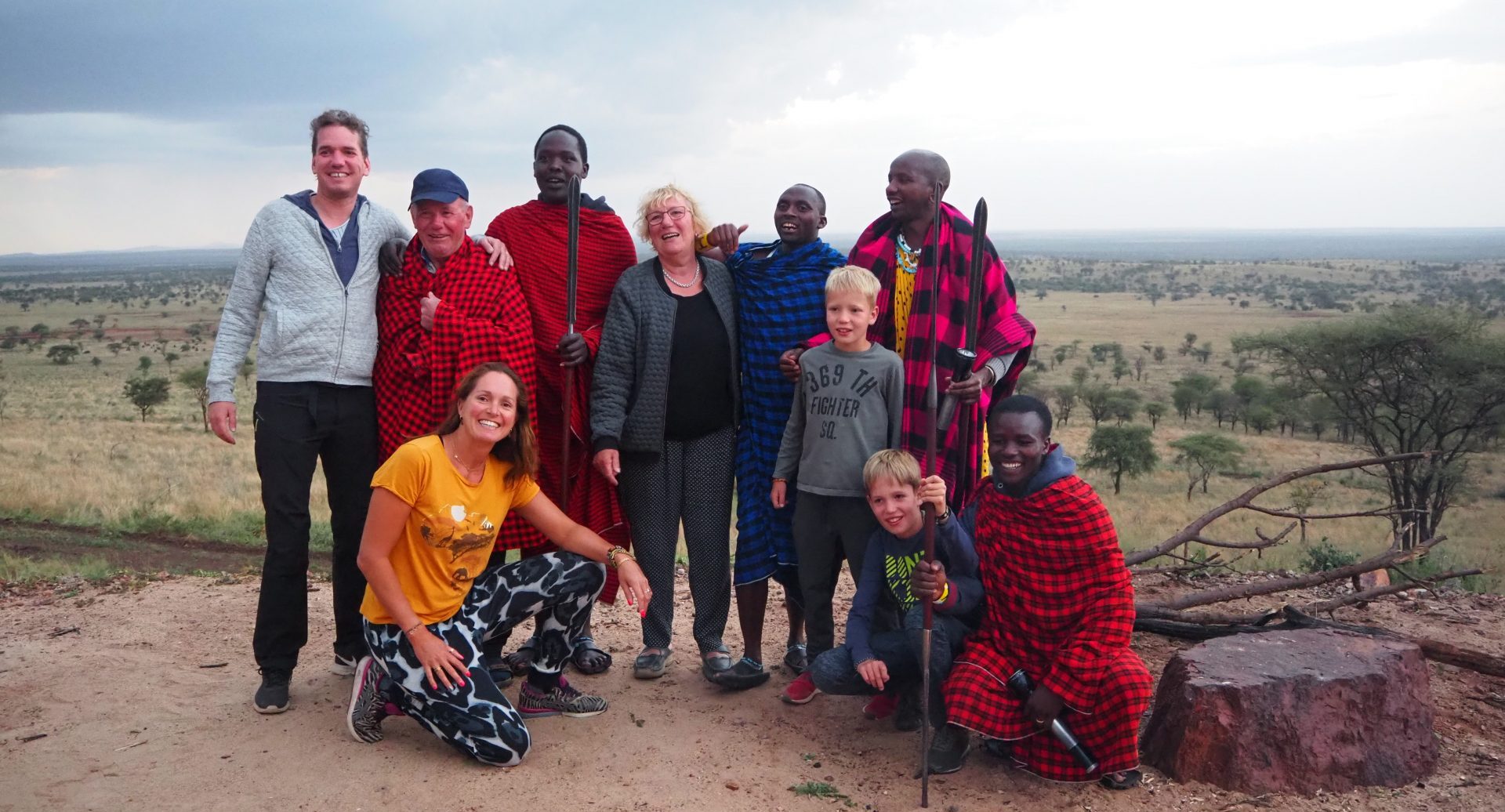 famile met opa oma zoon en schoondochter en kleinkinderen met dire masai mannen tijdens een bezoek aan de masai in tanzania