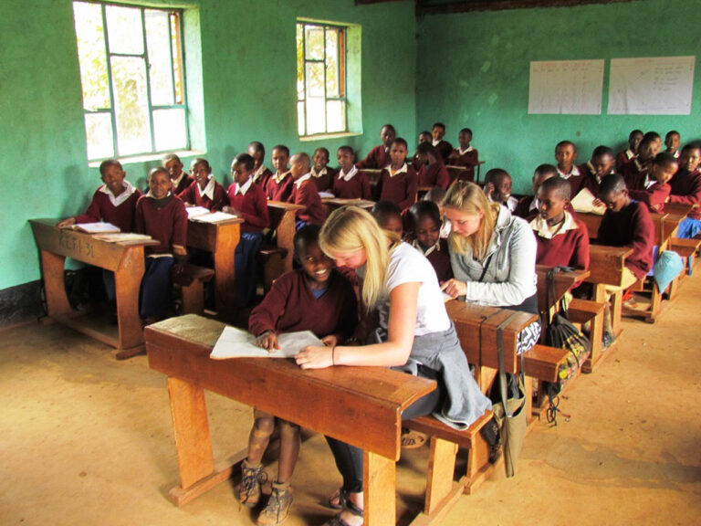 klas met jonge kinderen op safari en 50 leerlingen zittend in een schoolbank bij een bezoek aan een school cultuur activiteit tanzania