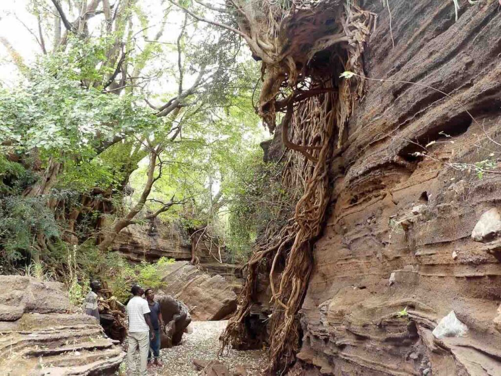 3 mensen die omhoogkijken naar een rots tijdens het wandelen van de canyon walk bij lake chala tanzania