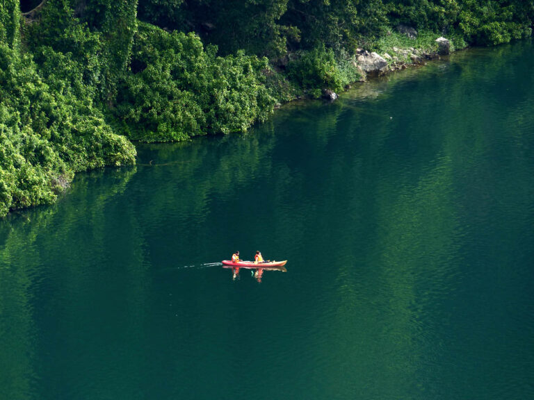 van bovenaf een uitzicht op het groene meer chala met een kayak en twee mensen