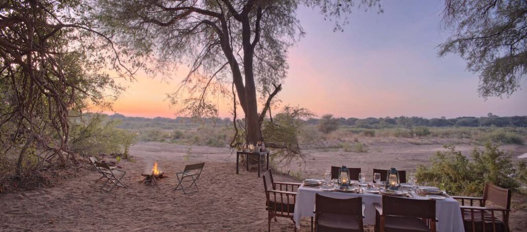 dineren in stijl aan een tafel met 6 stoelen en een kampvuur tijden een fly in safari in ruaha tanzania