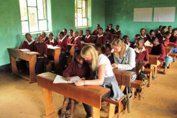 klas met jonge kinderen op safari en 50 leerlingen zittend in een schoolbank bij een bezoek aan een school cultuur activiteit tanzania