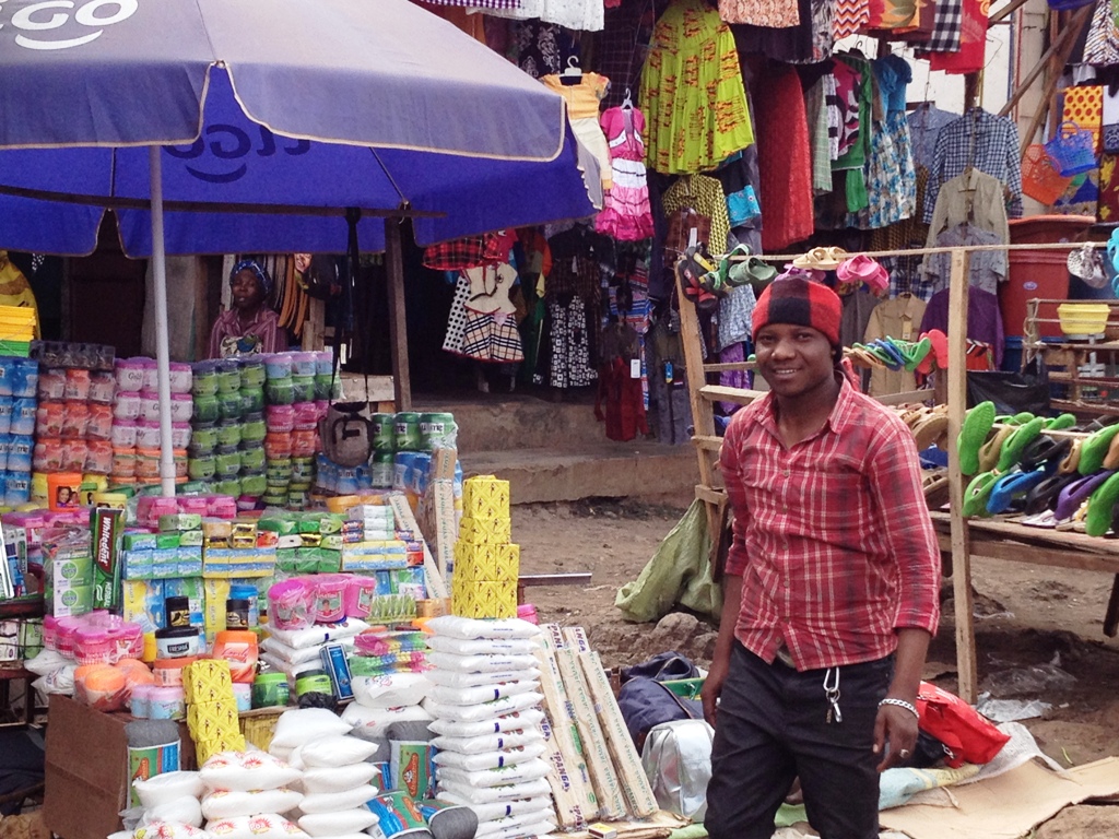 tanzaniaanse markt met kraampje vol schoonmaakspullen en de verkoper