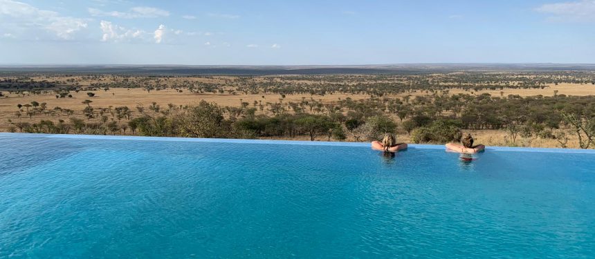 infinity pool zwembad met twee mensen erin uitkijkend over de serengeti vlakte kubu kubu tanzania