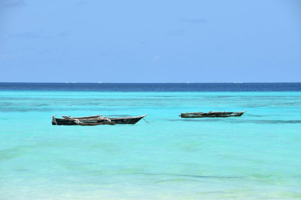 twee vissersbootjes in azuurblauwe zee bij Zanzibar strand