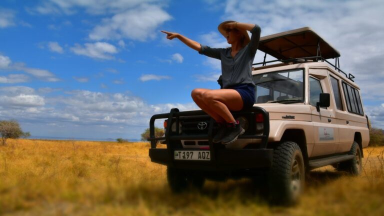 wijzende vrouw op de voorkant van een stoere 4x4 op huwelijksreis in tanzania