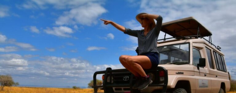 wijzende vrouw op de voorkant van een stoere 4x4 op huwelijksreis in tanzania