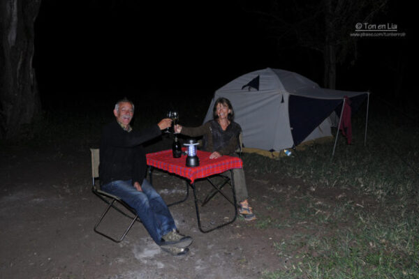 man en vrouw die proosten zittend aan een tafeltje op een camping in tarangire tanzania vogelsafari