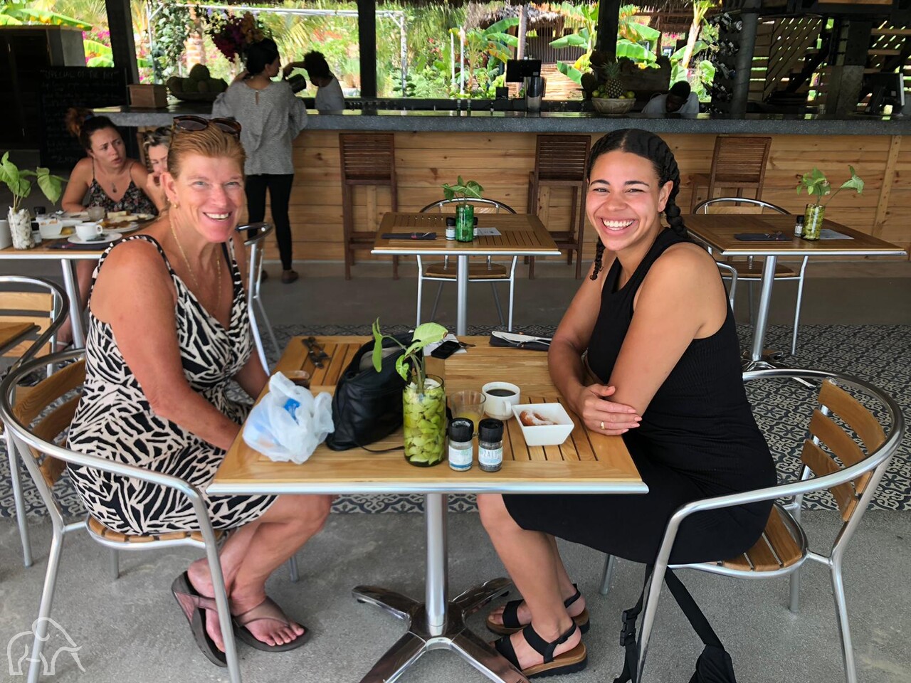 twee vrouwen zittend aan een tafeltje, lachend bij een hotel op zanzibar