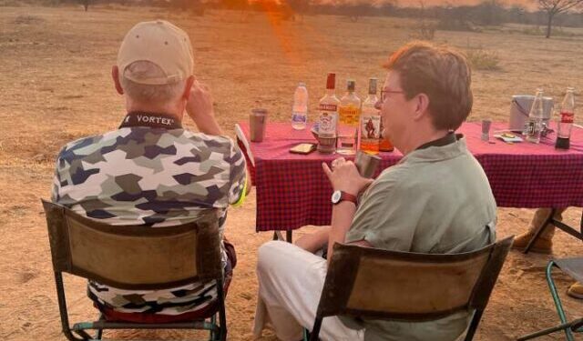 zittende man en vrouw tijdens een sundowner met een lekker drankje en een ondergaande zon in Ruaha national park tanzania