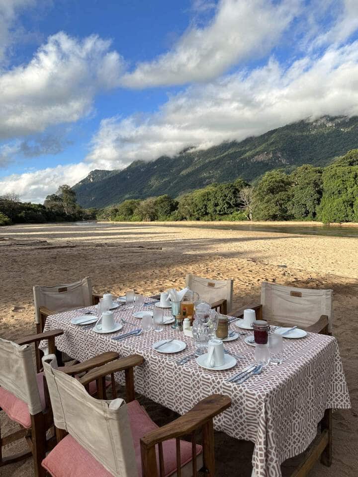 op een rivierbedding in lake manyara een mooi gedekte tafel met stoelen erom voor de lunch