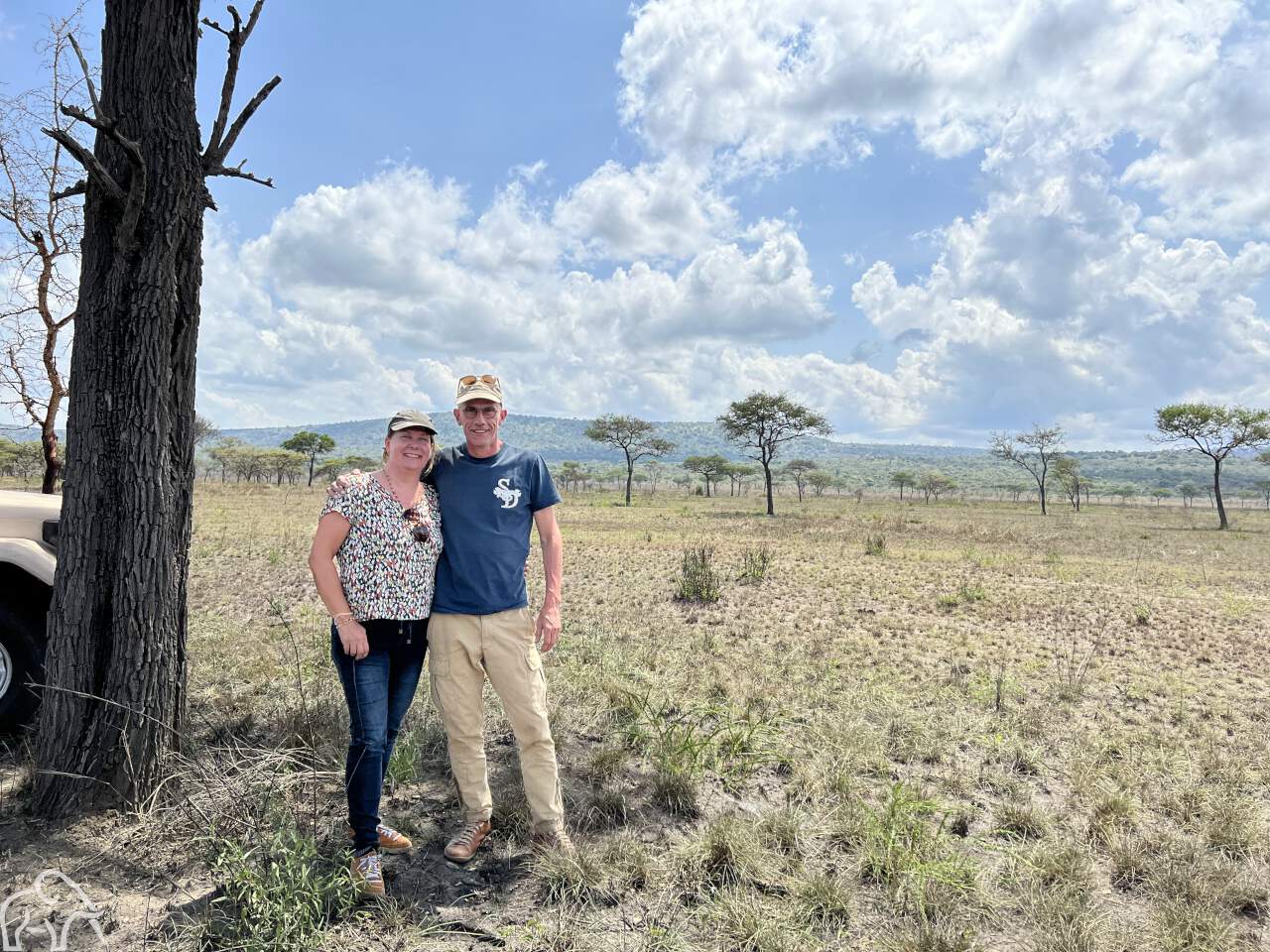 Over ons. Safari Tanzania. Eigenaren Martin en Wilma van Droomreis Tanzania tijdens een inspectiereis staand bij een boom op de vlaktes van de Serengeti