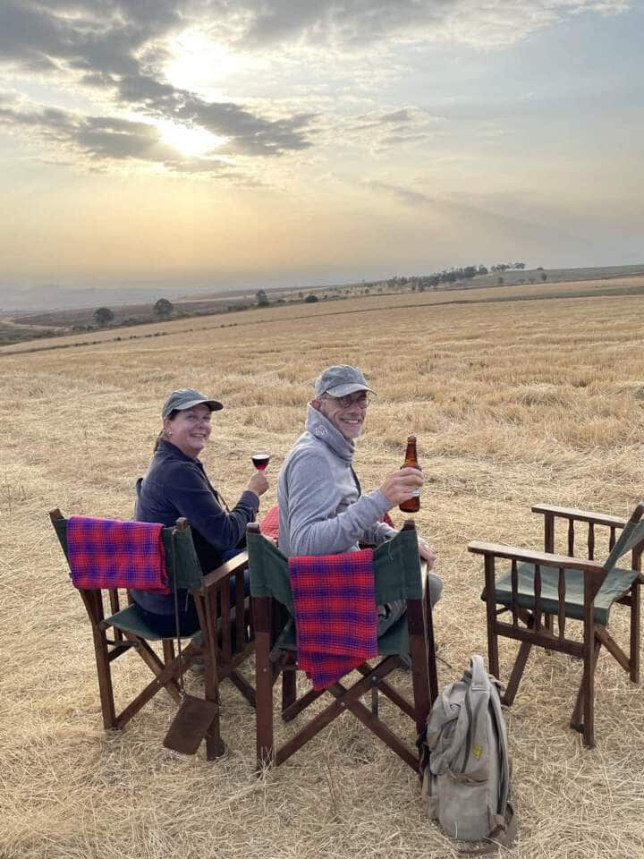 Martin en Wilma de eigenaren van Droomreis Tanzania zitten en proosten tijdens een sundower bij Simba Farm.  