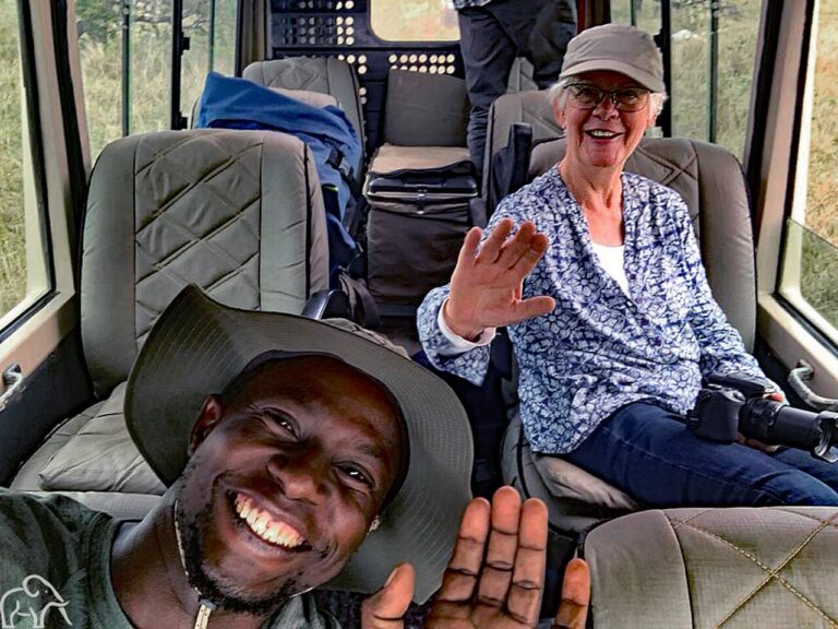 Reiservaring safari Tanzania. Selfie van gids in de safariauto met een vrouwelijke gast achterin tijdens een gamedrive