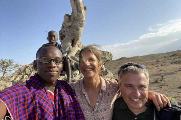 safari Tanzania reiservaring. Twee gasten en hun Masai gids met daarachter op een boom een jongetje die een selfie maken