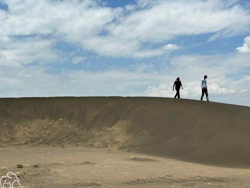 Eigenaren Wilma en Martin van Droomreis Tanzania boven op de shifting sands in Tanzania. Het zwarte zand van de het heuveltje verplaats zich door de wind steeds verder 