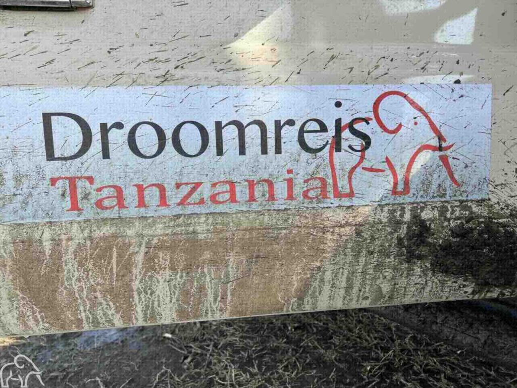 Droomreis Tanzania reclame op de zijkant van de safari auto. Weg van de gebaande paden want het is helemaal vies