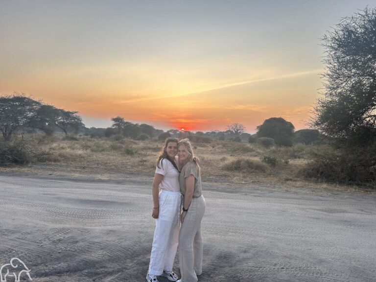 twee reizigers poseren met de ondergaande in Ndutu Tanzania