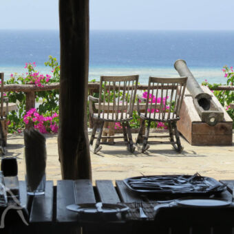 the manta resort terras van een lodge met stoeltjes en tafeltjes een oud kanon uitkijkend over de indische oceaan