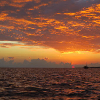zonsondergang oranje afgewisseld met grijze wolken tijdens een zonsondergang gezien vanaf een bootje op zee bij Mafia eiland