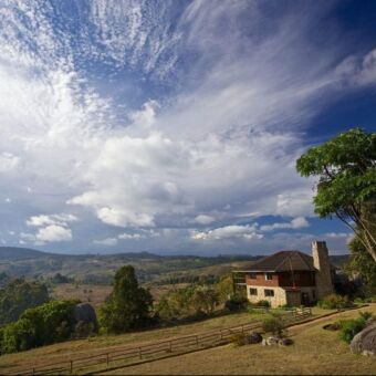uitzicht lodge vanaf een heuvel genomen uitzicht over een heuvelachtig landschap met groene velden en dichte bossen en daartussen de mufindi-highland-lodge