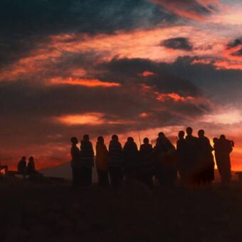 Dansende Masai bij een oranje hemel van de ondergaande zon