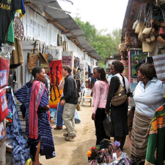 nauw straatje in Arusha met souvenirs winkeltjes en vier vrouwen die met elkaar praten