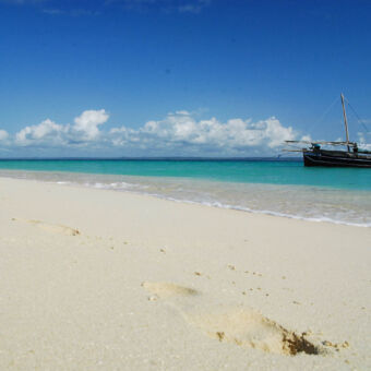 boot bij Maziwe strand met uitzicht op de indische oceaan met een grote vissersboot met mast maziwe eiland tanzania