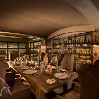 zeer luxe diner ruimte met grote eetkamer fauteuils lange gedekte tafel en heel veel flessen wijn langs de muur in de buurt van ngorongoro