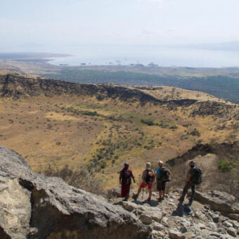 uitzicht op Lake Natron vier mensen licht bepakt op rotsen met uitzicht op lake natron tijdens een meerdaagse wandeling in tanzania