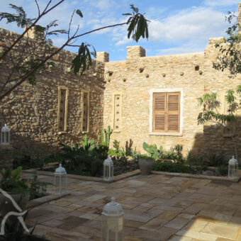 doordachte gebouwstructuren buitenkant van een luxe lodge in oosterse stijl recht en strak en een buitengevel die geel is en opgebouwd uit kleine stenen vlakbij lake Eyasi tanzania