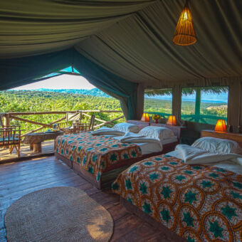 family tent twee grote familie kamer met tweepersoonsbedden mooi opgemaakt met kleurige dekbedden in een canvas tent op palen en uitzicht op rohotia valley
