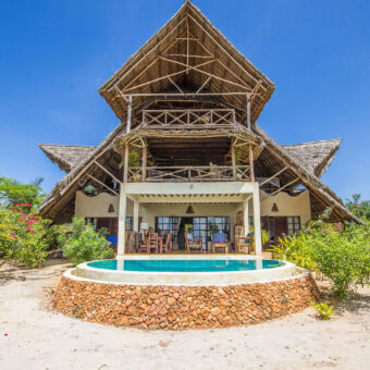 Zanzibar Milele villa net op het strand een rond zwembad en villa gebouwd met houten palen een schuin rieten dak met drie verdiepingen tussen het groen op Zanzibar