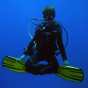 haal je PADI duikbrevet jonge duiker zwevend onderwater in kleermakerszit tijdens een duikcursus bij divepoint zanzibar