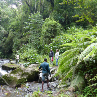 drie mensen die op rotsen staan aan de oevers van een rivier kijkend naar mensen in de rivier vlakbij arusha tanzania