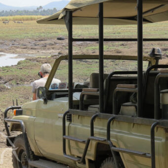 wildlife spotten open safari auto met canvas dak met daarvoor een man met camera en heel veel hippo's in een poel bij katavi tanzania