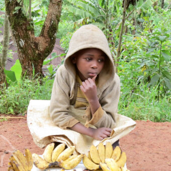 bananen verkopen jong meisje met capuchon op haar hoofd aan de kant van de weg verkoopt bananen