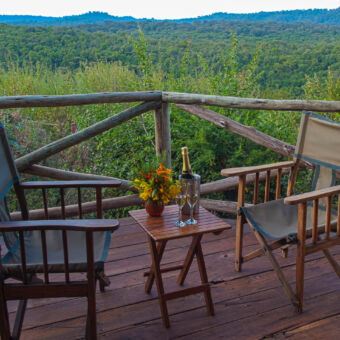 enjoy the view! veranda voor de tent waarop twee stoelen staan en een tafeltje en een prachtig uitzicht over het groene rhotia valley