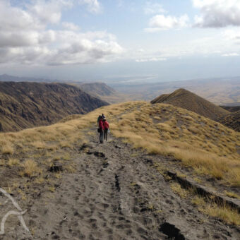 onderweg door het heuvelachtige landschap gezin met jonge kinderen en gids onderweg over de toppen van de bergen tijdens Empakai naar Lake Natron meerdaagse wandeling tanzania