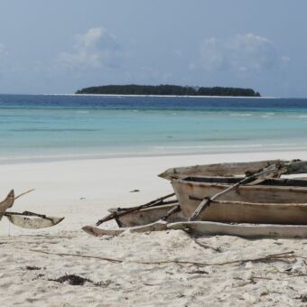 uitzicht over een azuurblauwezee op Zanzibar met bootjes op de voor grond