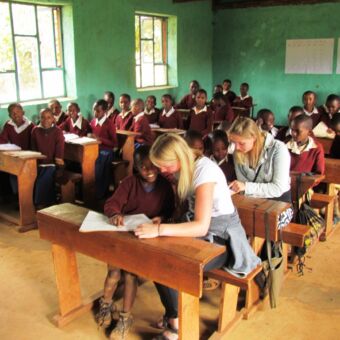 klas met jonge kinderen op safari en 50 leerlingen zittend in een schoolbank bij een bezoek aan een school cultuur activiteit tanzania