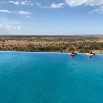 infinity pool zwembad met twee mensen erin uitkijkend over de serengeti vlakte kubu kubu tanzania