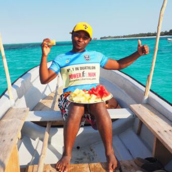 tanziaanse man met schaal vers fruit op zijn schoot tijden boottocht zanzibar huwelijksreis